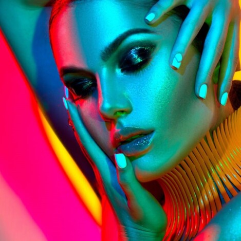 Corso Armocromia Primo piano di una donna con makeup luminoso e luci colorate che esaltano i toni della pelle
